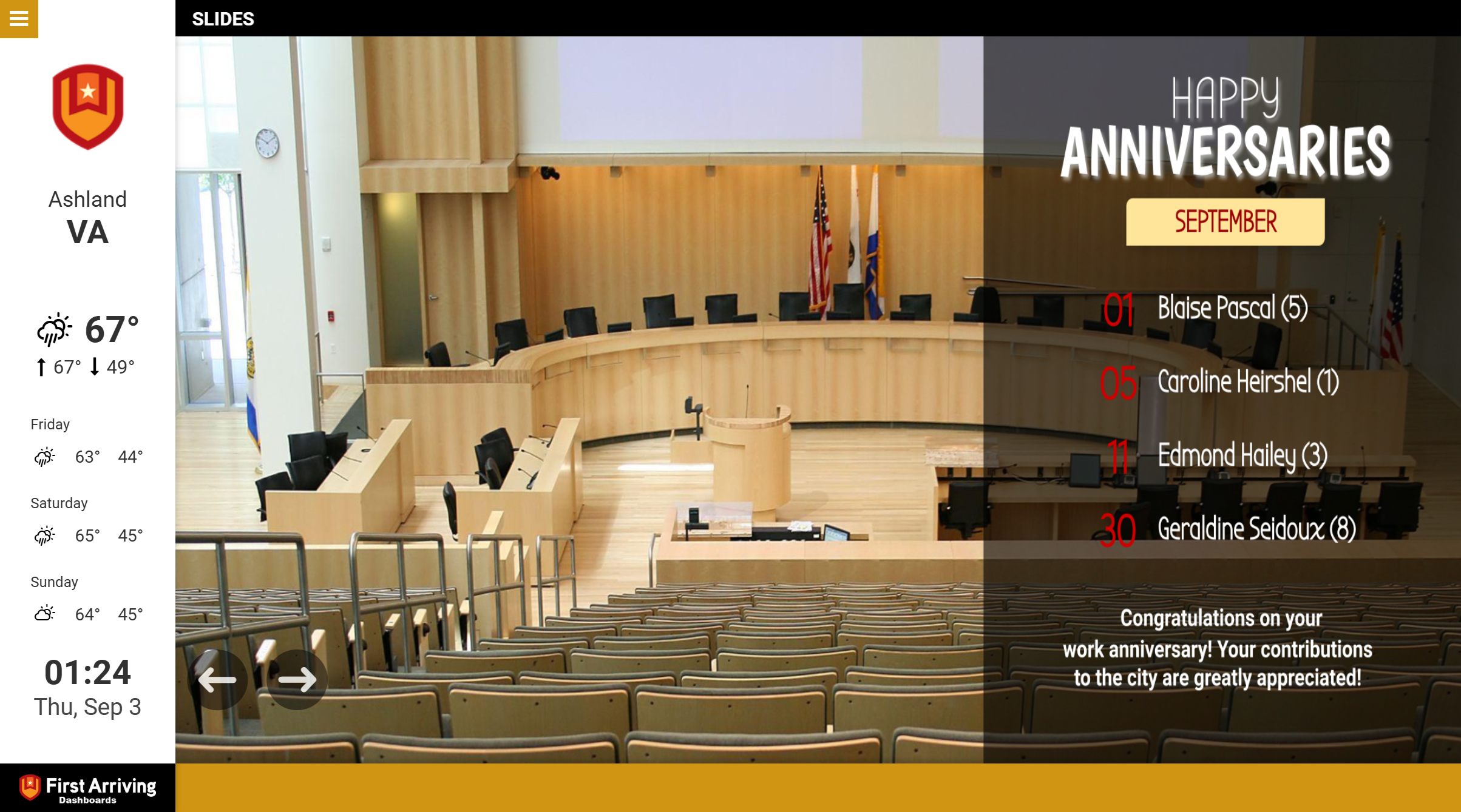 Empty city council chamber with curved wood desk and American flag, September anniversaries celebration slide displayed
