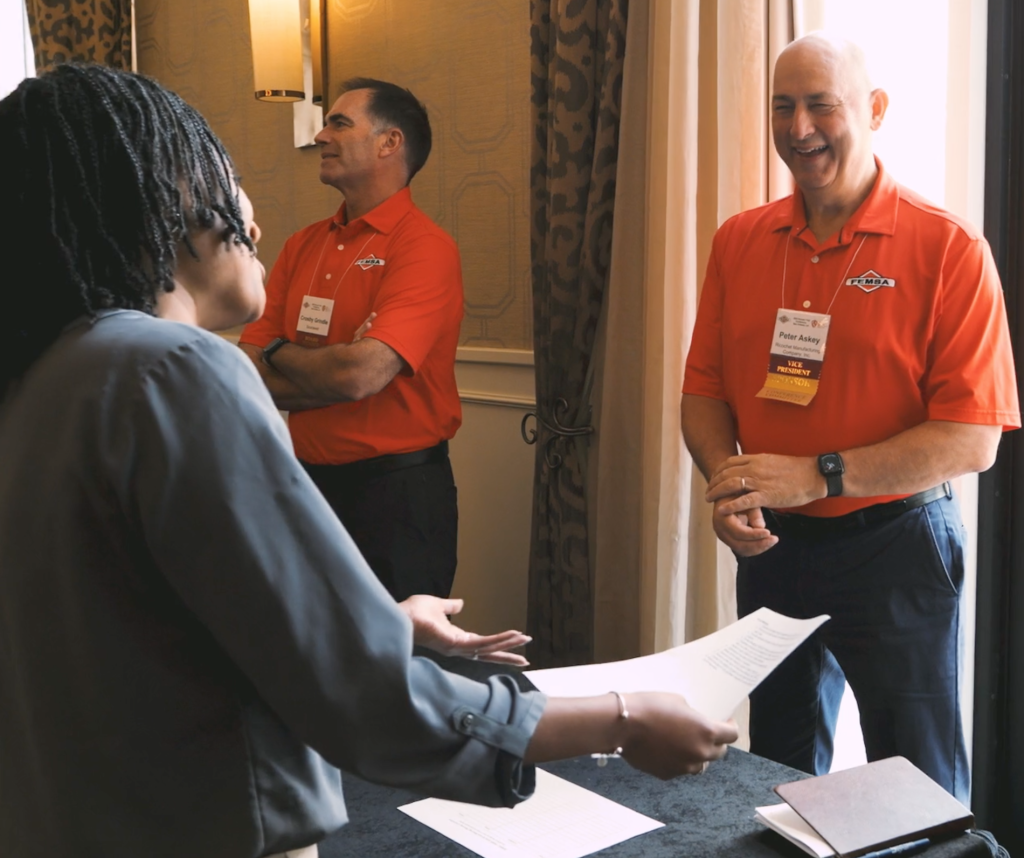 Attendees with conference badges exchanging materials at a trade show