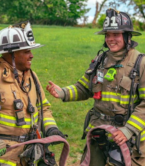 Two firefighters in full gear talking outdoors